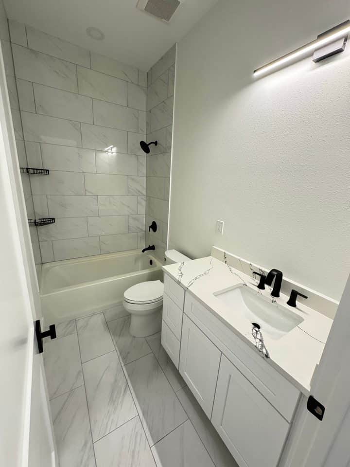 Finished bathroom marble tile black fixtures | bathroom remodeling in Port Charlotte, FL by Sosnin Builders
