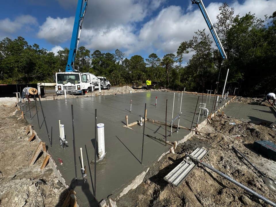 Slab pour framed by pump truck booms | construction work in progress in North Port, FL by Sosnin Builders