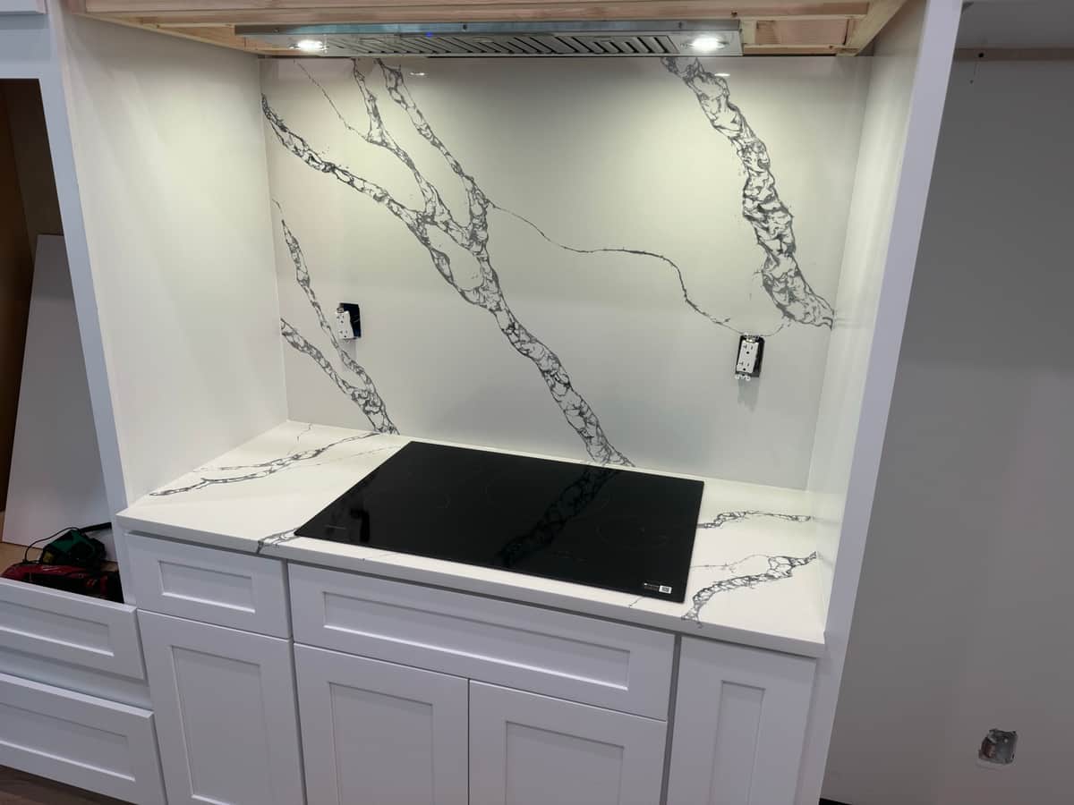 Quartz slab backsplash and cooktop detail in a Port Charlotte kitchen by Sosnin Builders