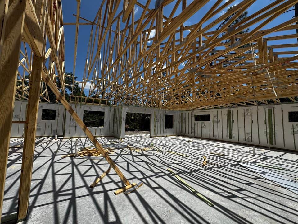 Roof trusses overhead against blue sky | framing work in Port Charlotte, FL by Sosnin Builders