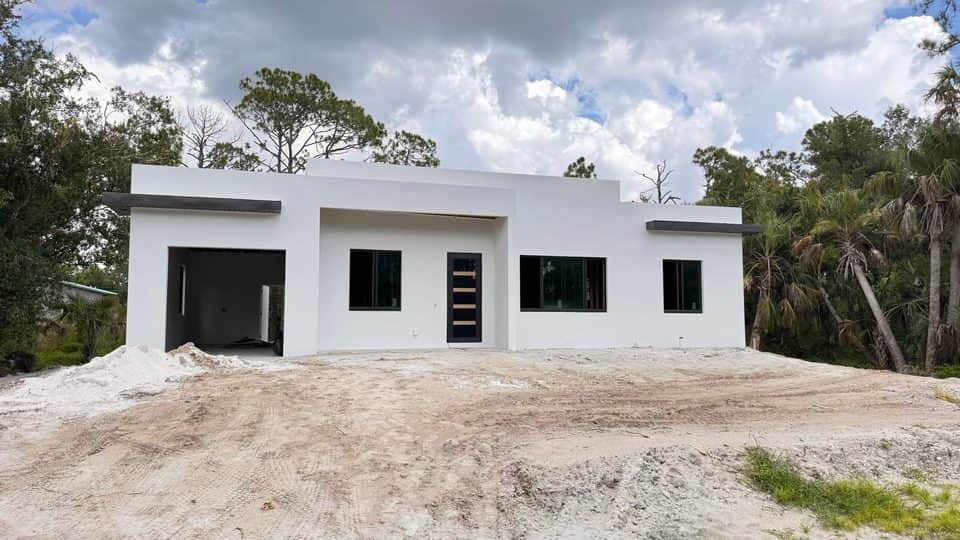 White stucco home exterior, grading underway | new home construction in North Port, FL by Sosnin Builders