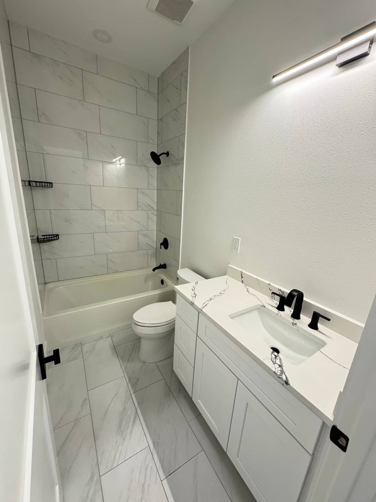 Finished bathroom marble tile black fixtures | bathroom remodeling in Port Charlotte, FL by Sosnin Builders