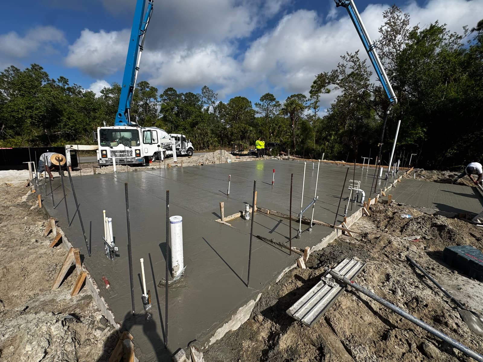 Slab pour framed by pump truck booms | construction work in progress in North Port, FL by Sosnin Builders