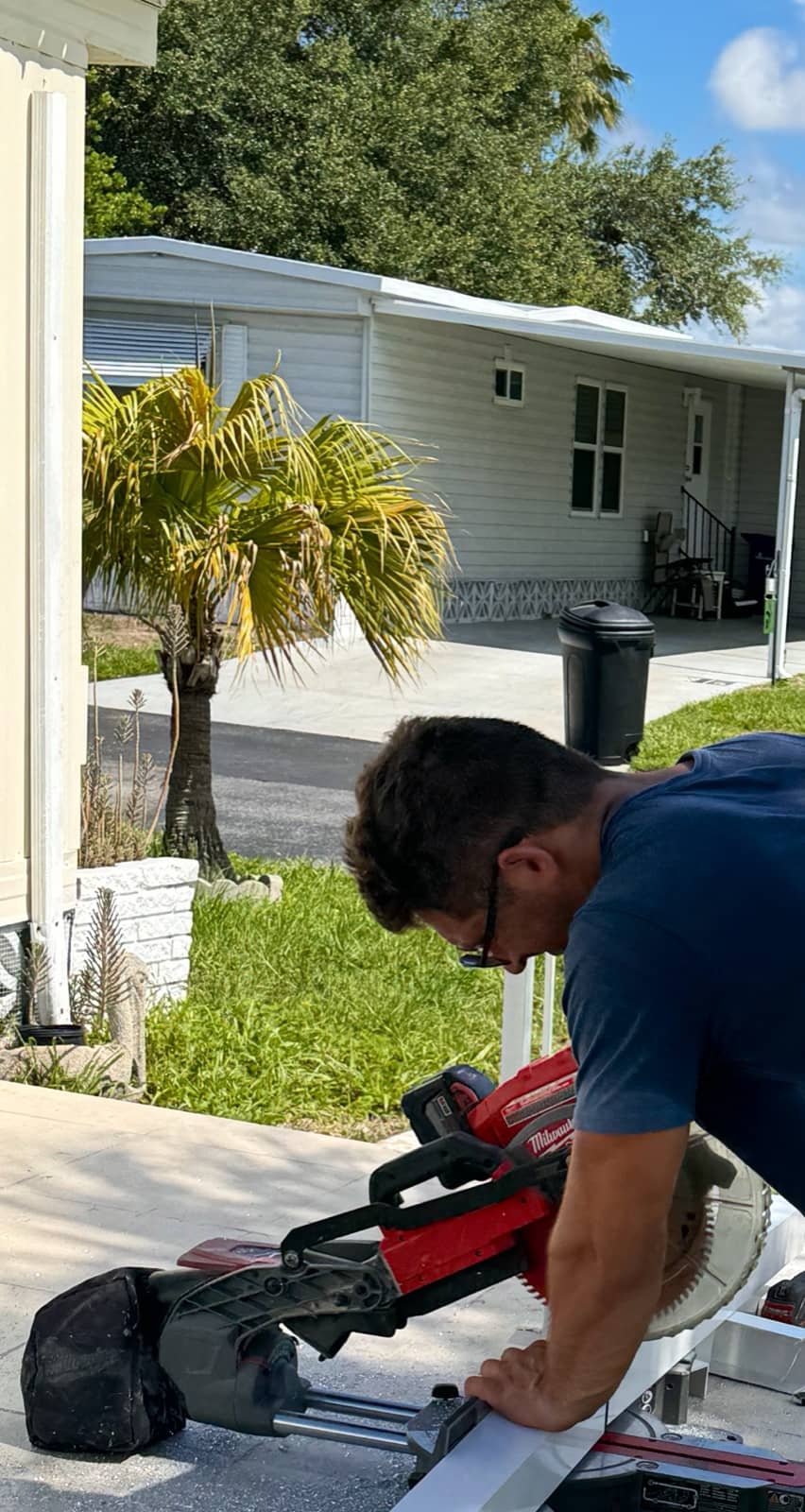 Worker cutting trim on miter saw | construction work in progress in Venice, FL by Sosnin Builders