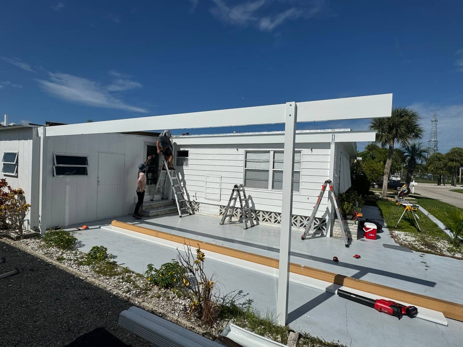 Carport beam installation, crew on ladders | construction work in progress in Venice, FL by Sosnin Builders