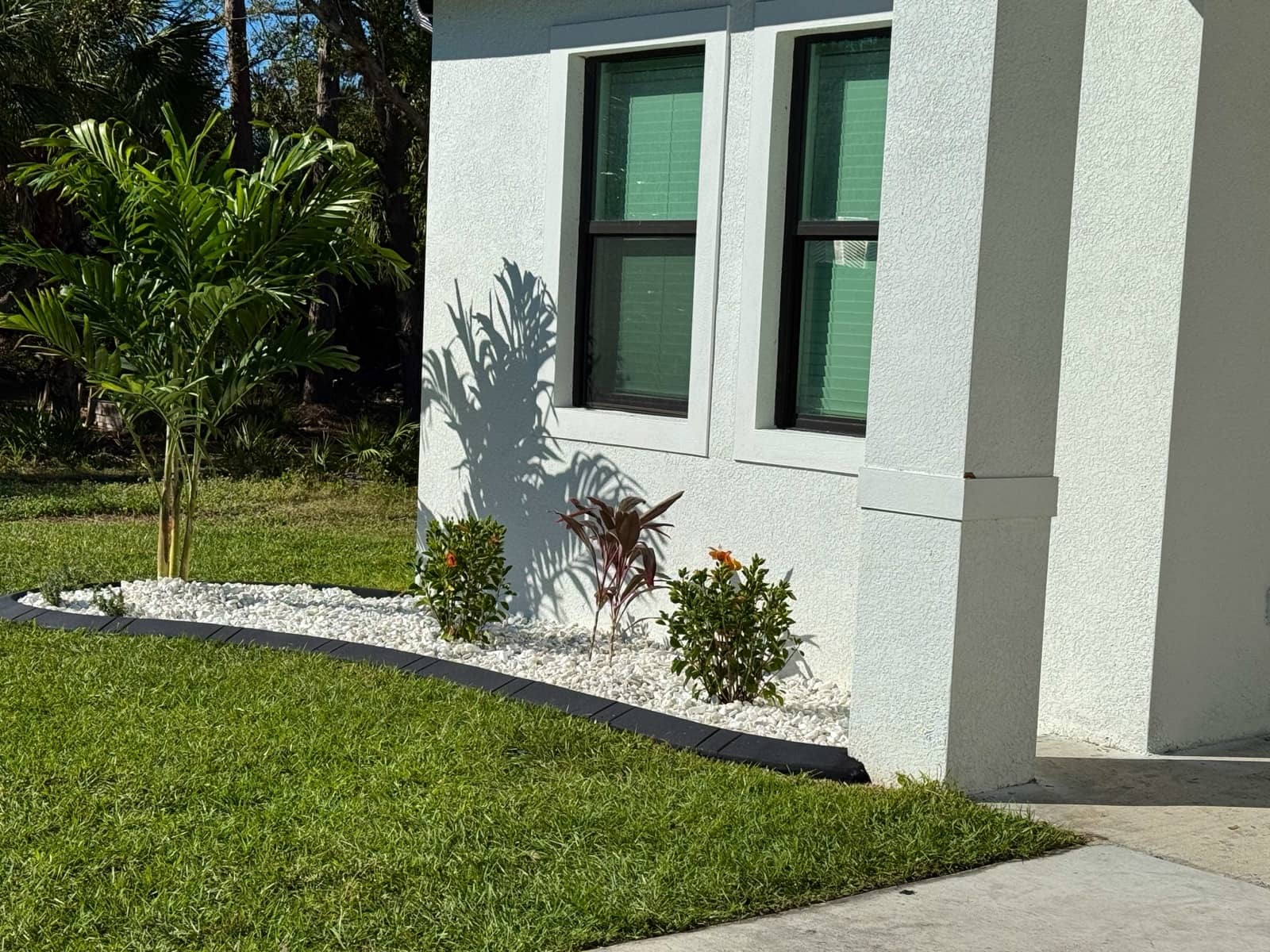 White-rock landscaping bed at home corner | custom home building in Port Charlotte, FL by Sosnin Builders