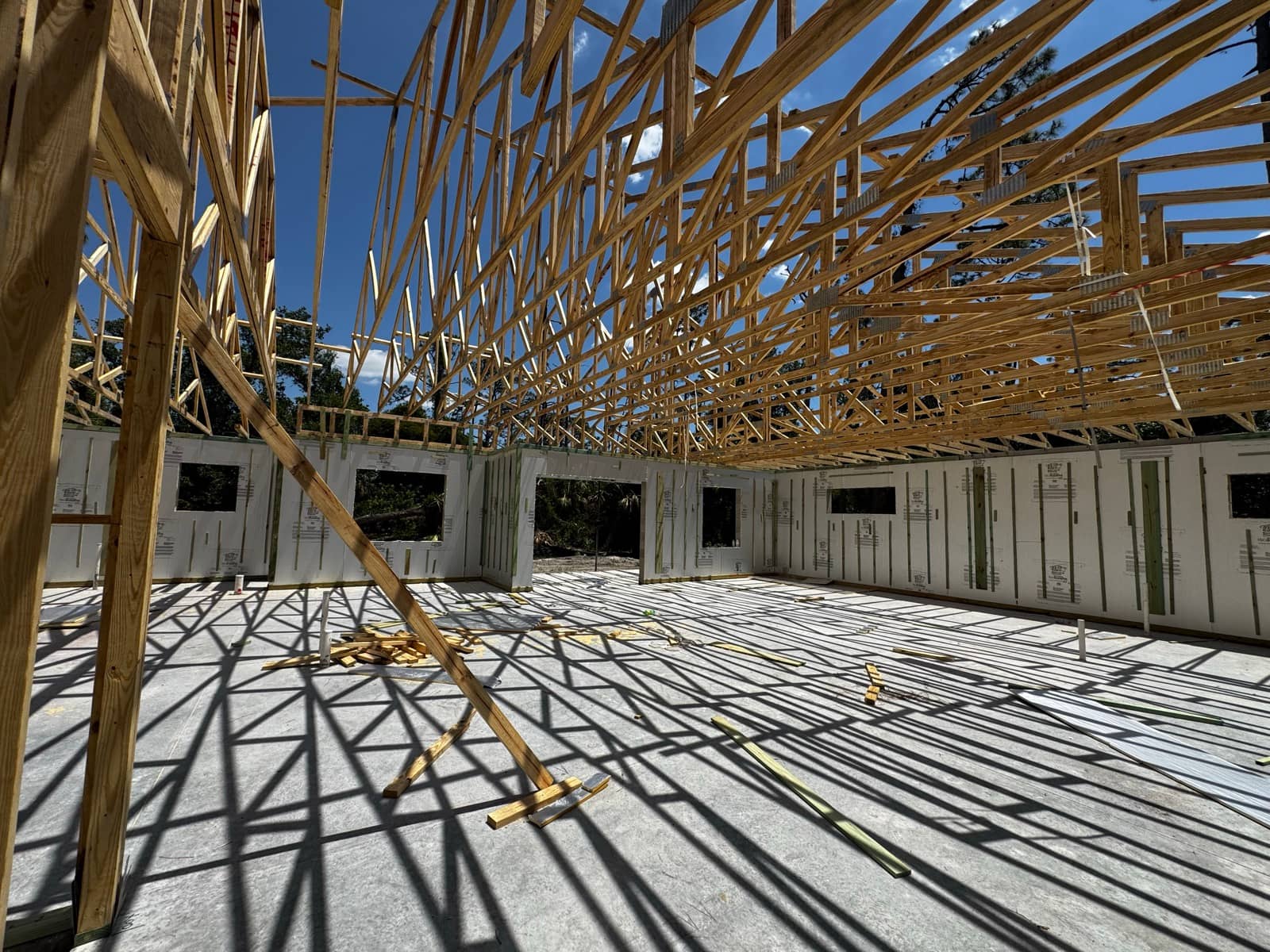 Roof trusses overhead against blue sky | framing work in Port Charlotte, FL by Sosnin Builders