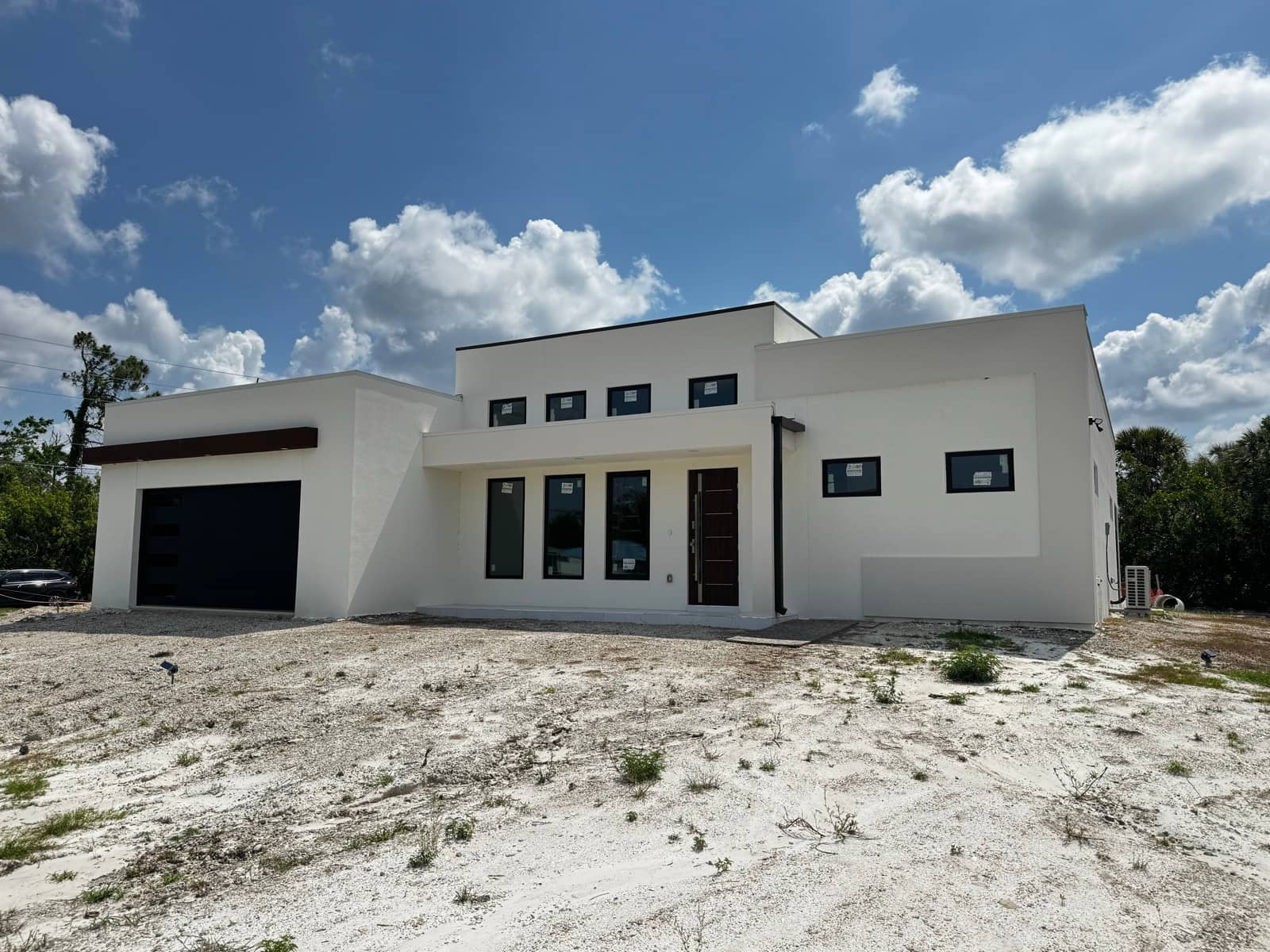 Modern white home exterior with dramatic clouds | new home construction in Englewood, FL by Sosnin Builders