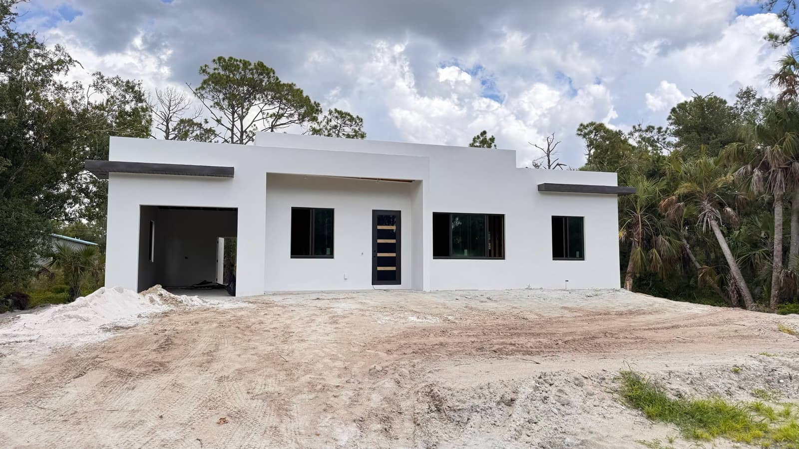 White stucco home exterior, grading underway | new home construction in North Port, FL by Sosnin Builders
