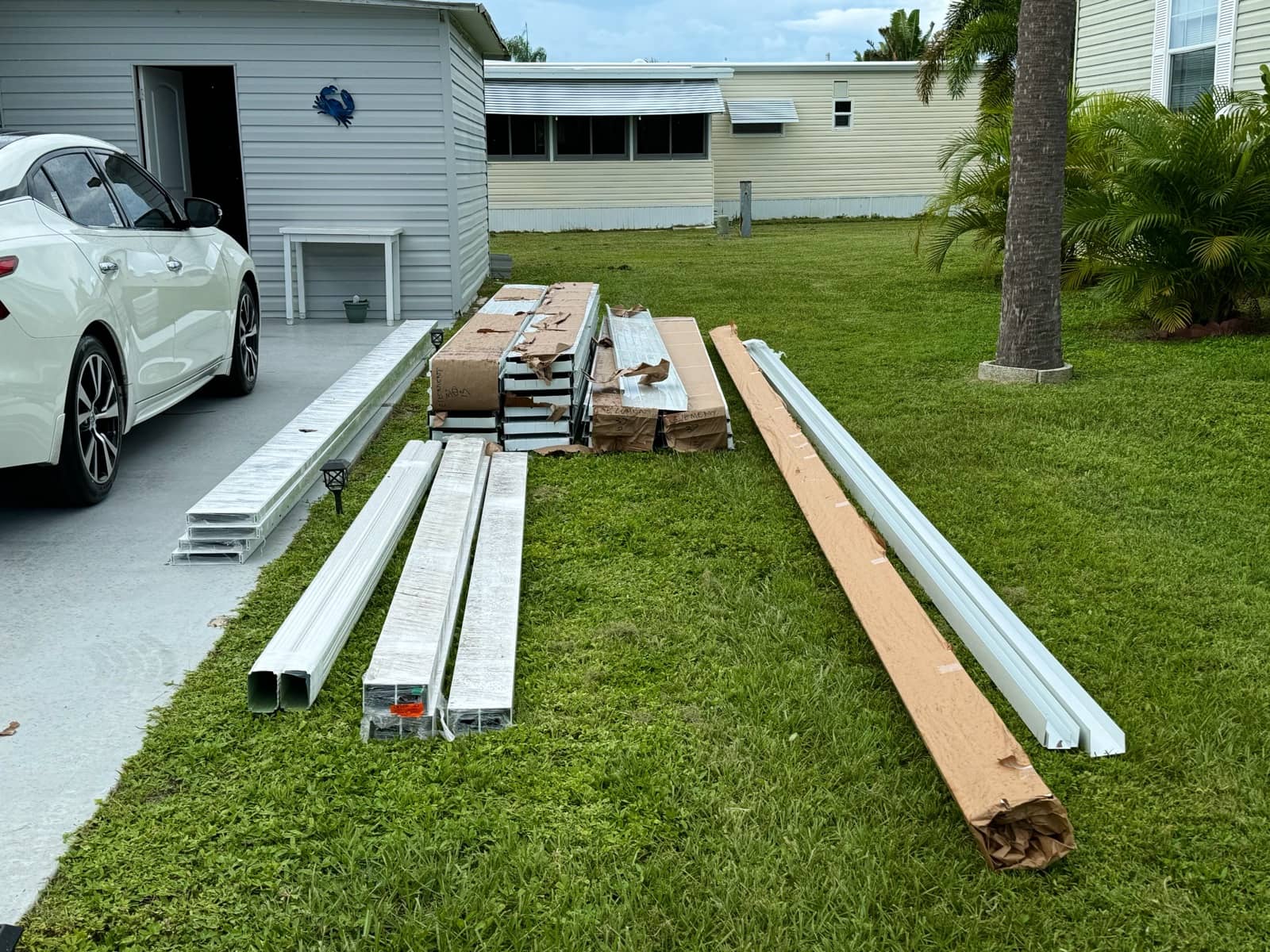 Screen enclosure materials staged on lawn | screen enclosure work in Venice, FL by Sosnin Builders
