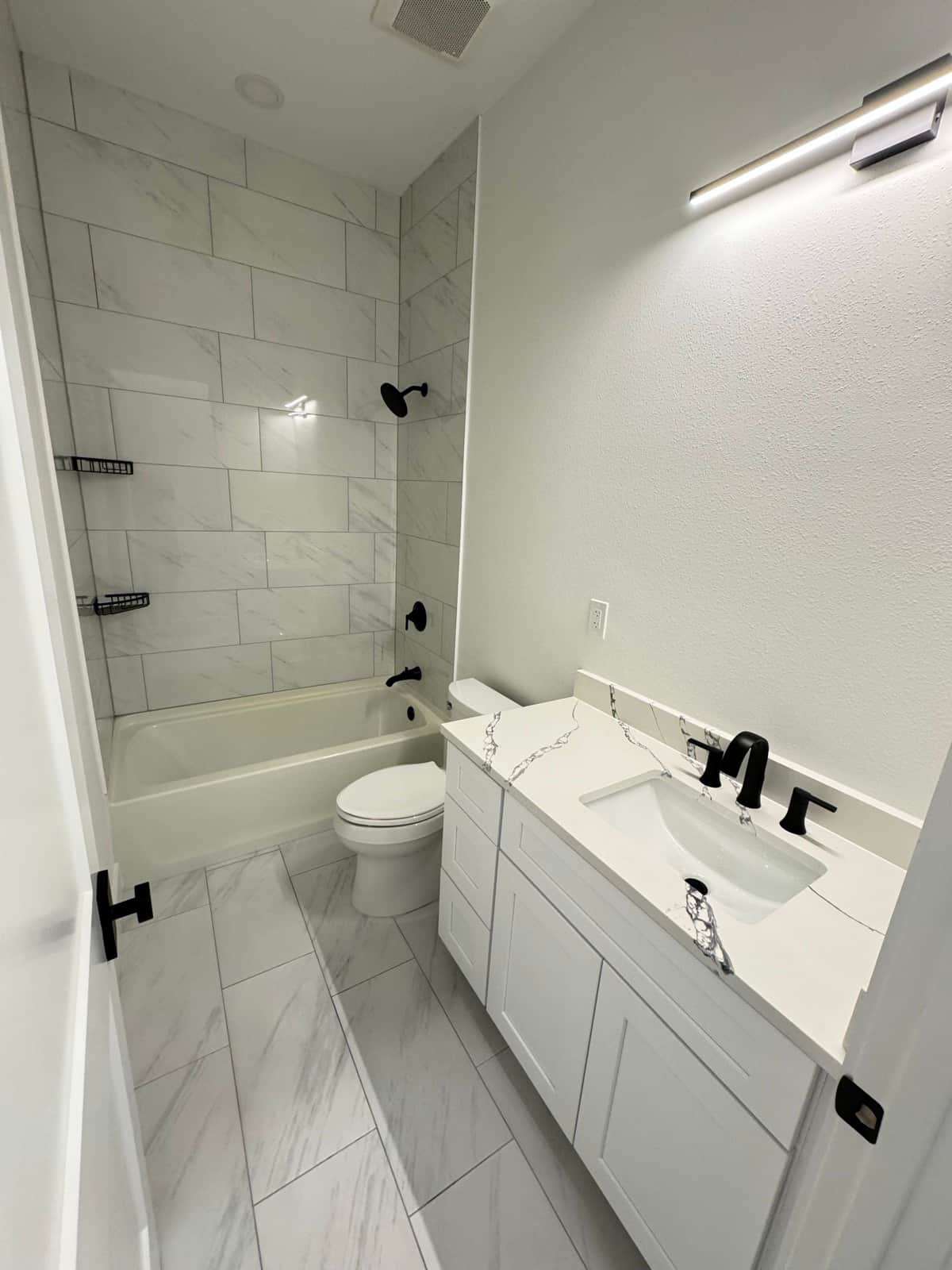 Finished bathroom marble tile black fixtures | bathroom remodeling in Port Charlotte, FL by Sosnin Builders